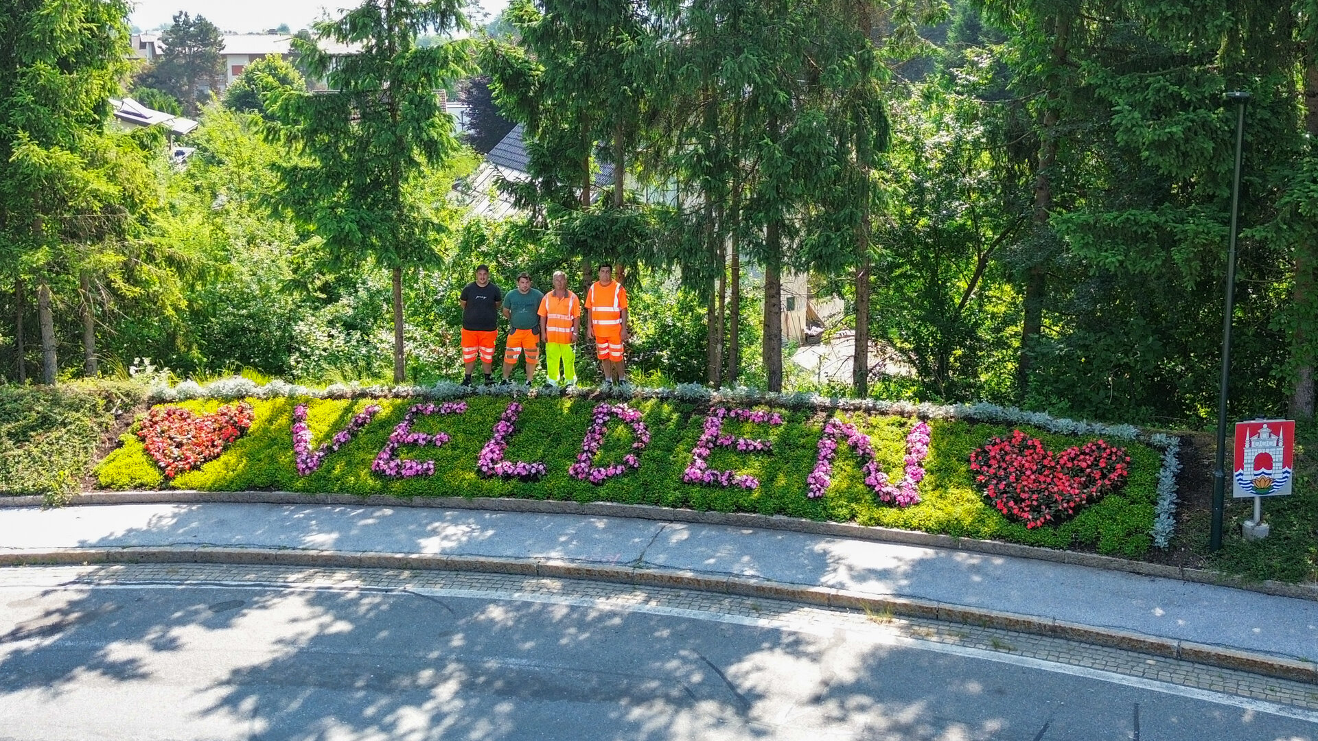 Foto: KK/VTG Die Mitarbeiter des Bauhofs und des Gärtnerteams posieren vor dem frisch gepflanzten Blumen im Velden-Schriftzug