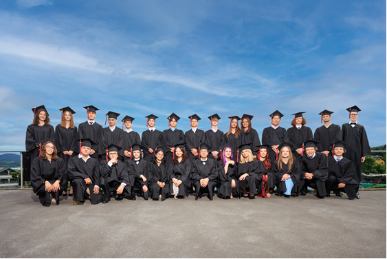 Foto: KK/Simone Attisani Photography Die Schüler und Schülerinnen der ISC Abschlussklasse posieren in schwarzen Roben für ein Gruppenfoto.