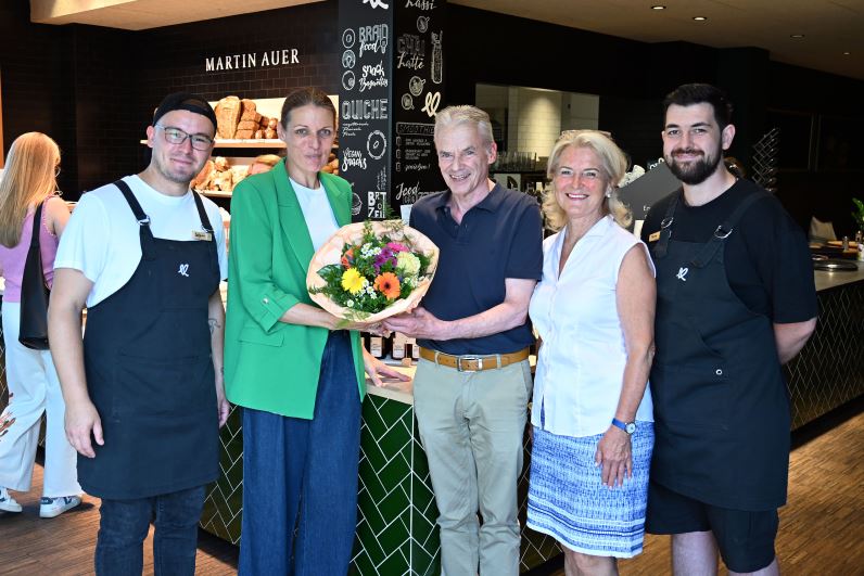Bürgermeister Ferdinand Vouk, GV Dr. Margit Heissenberger, Frau Neuschitzer und zwei Mitarbeiter der Martin Auer Filiale posieren gemeinsam für ein Foto. Zur Eröffnung der Filiale überreicht Bgm. Vouk einen bunten Blumenstrauß. 